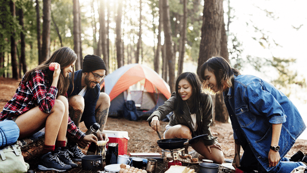 group of friends enjoying cooking while camping