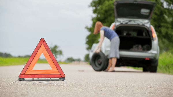 woman changing the flat tire of a car