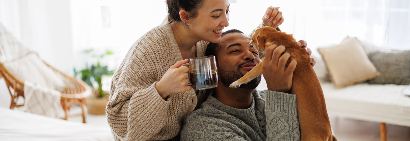 blog feature critical illness insurance man on couch with woman behind him smiling at their puppy