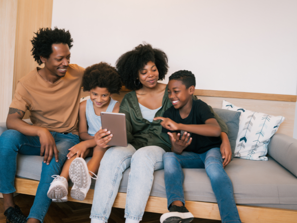 mom dad daughter and son on couch scrolling on a tablet